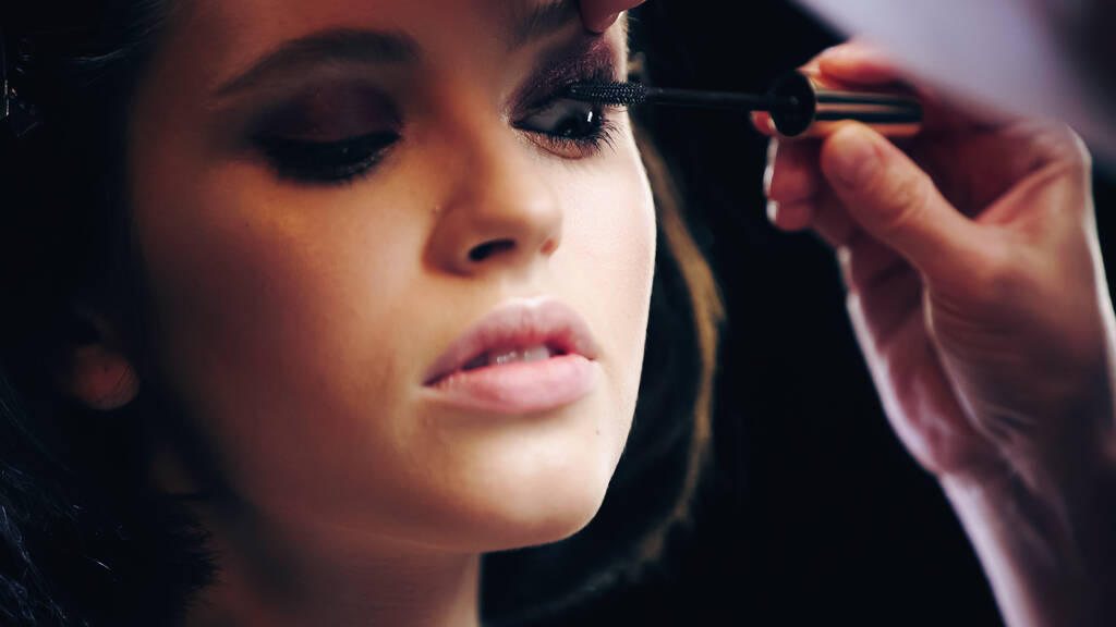 Make-up-Artist trägt schwarze Mascara auf Wimpern des Models auf - Foto, Bild