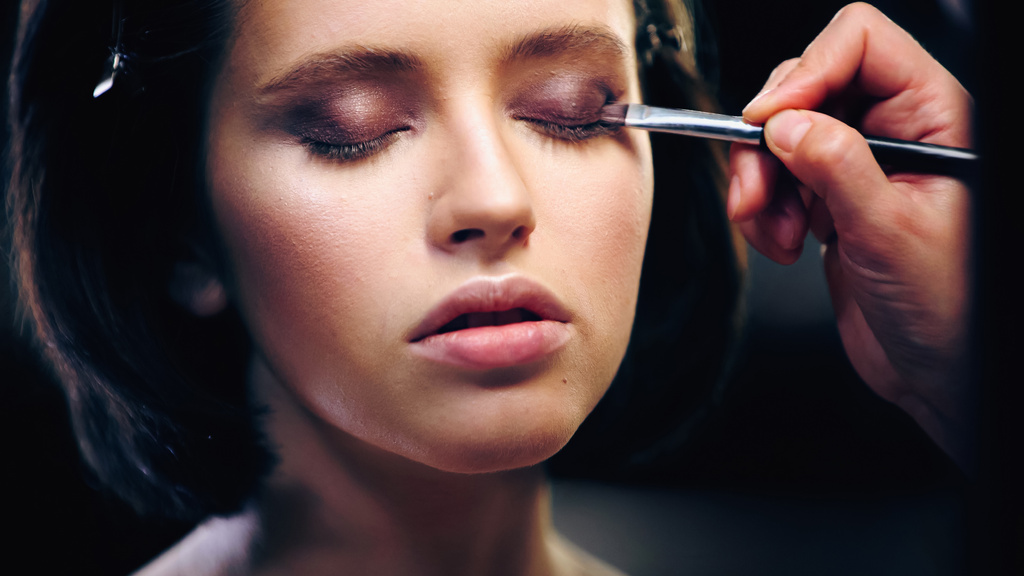 makijaż artysta stosując cień do powiek z pędzlem kosmetycznym na powiekach młodej kobiety - Zdjęcie, obraz