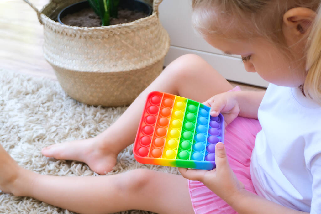 Девушка играет с поп-это сенсорная игрушка. Облегчение стресса и тревоги. Трендовая игра для детей, находящихся в стрессовом состоянии  - Фото, изображение