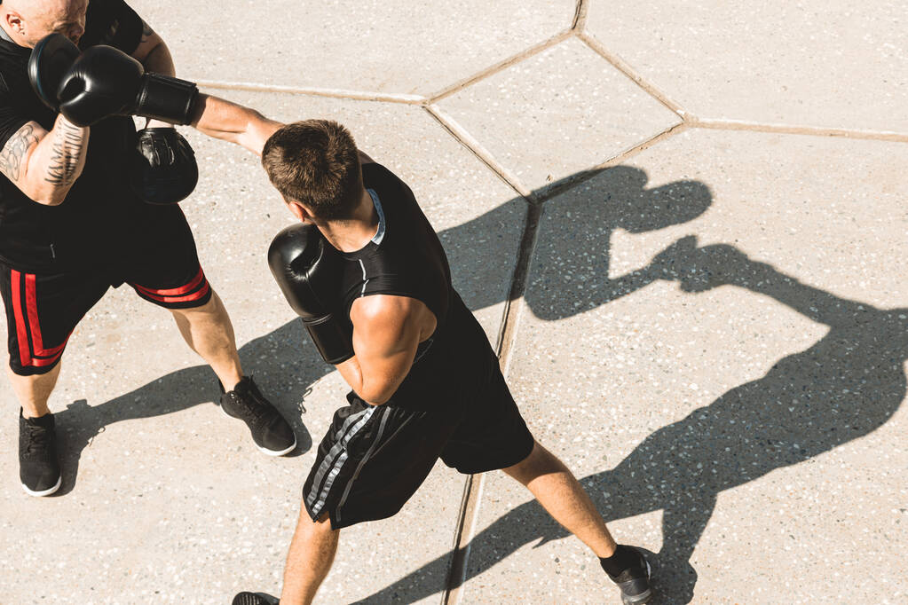 Két férfi edz és harcol odakint. A kesztyűs bokszoló edzővel edz. - Fotó, kép