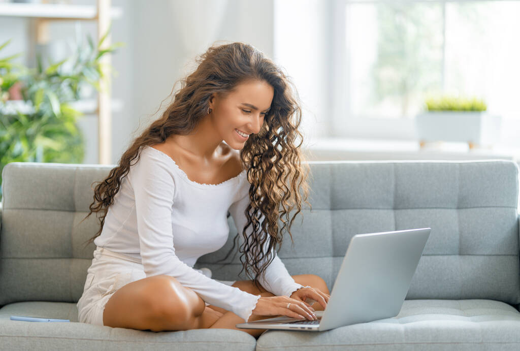 Glückliche junge Frau, die online studiert, Webinar, Podcast auf dem Laptop anschaut, Notizen macht, am Schreibtisch sitzt. E-Learning-Konzept. - Foto, Bild