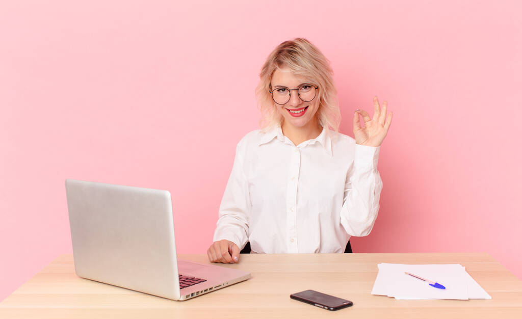 blonde pretty woman young pretty woman feeling happy, showing approval with okay gesture. workspace desk concept - Photo, Image
