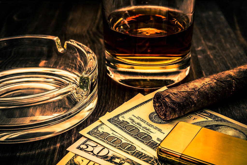 Egy pohár whiskey és egy kis pénz kubai szivarral és arany öngyújtóval. - Fotó, kép