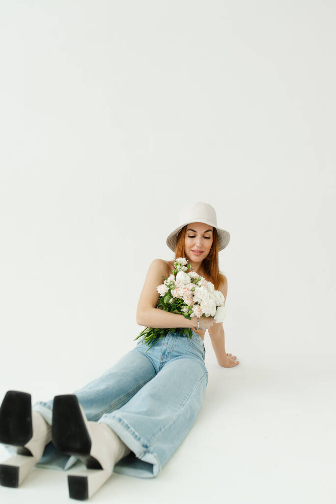 μοντέλο γυρίσματα στο στούντιο όμορφο κορίτσι σε ένα στερεό φόντο σε παγάμα και με ένα μπουκέτο λουλούδια - Φωτογραφία, εικόνα