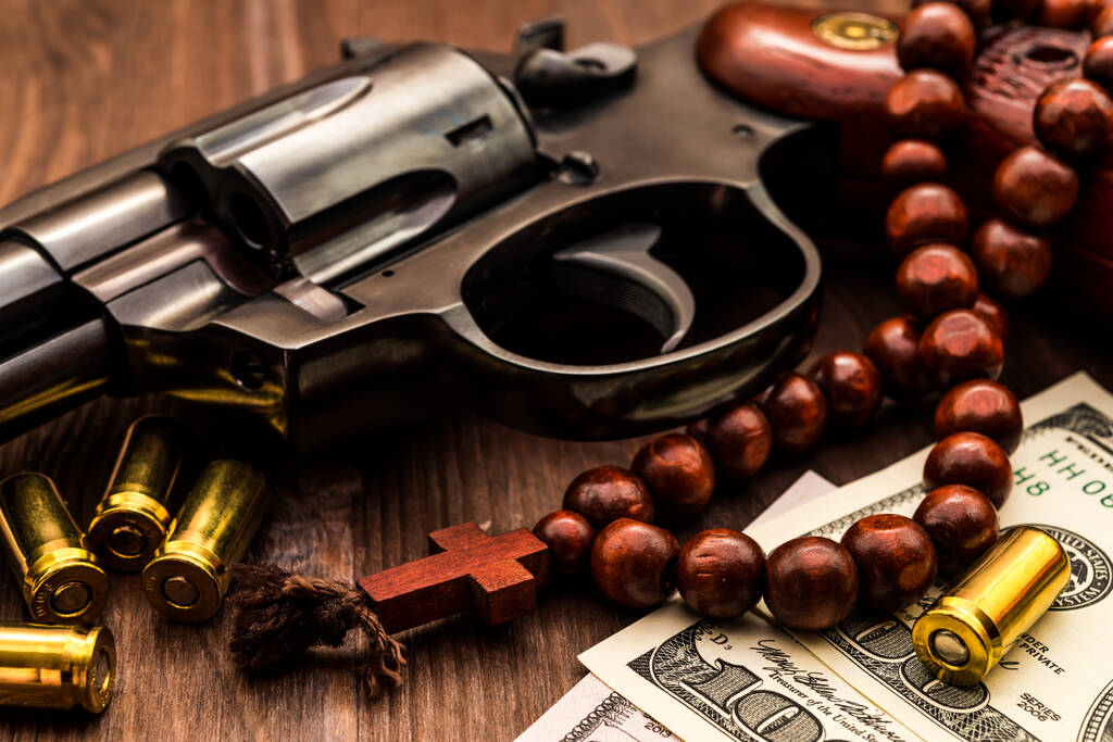 Revolver mit Patronen und Rosenkranz auf dem Holztisch. Schließen - Foto, Bild