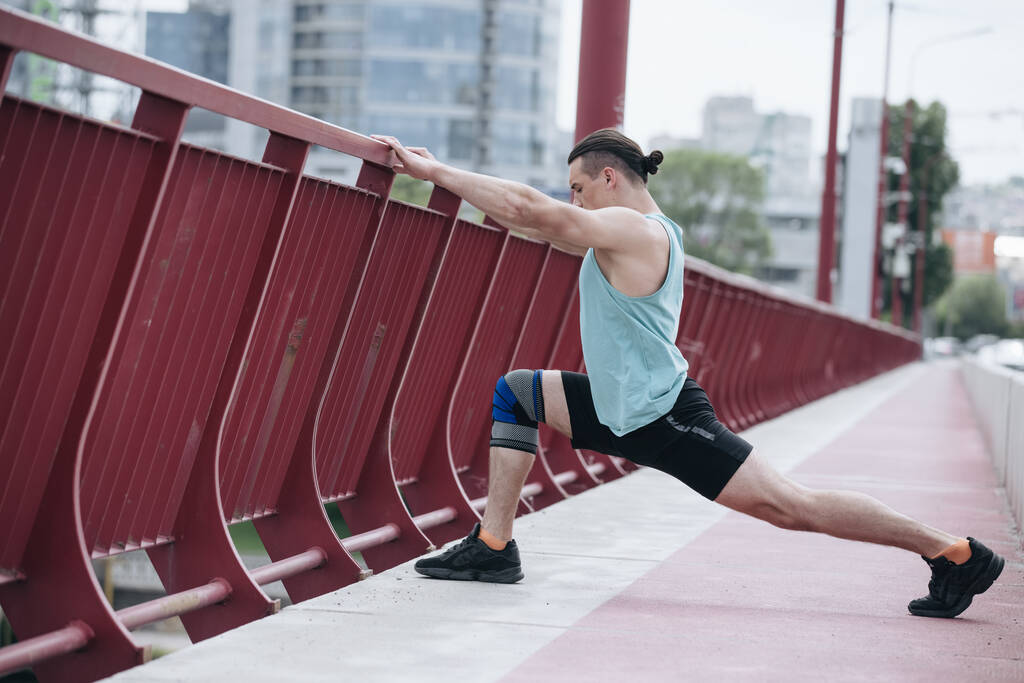 L'homme étire la jambe avant de courir sur un pont - Photo, image