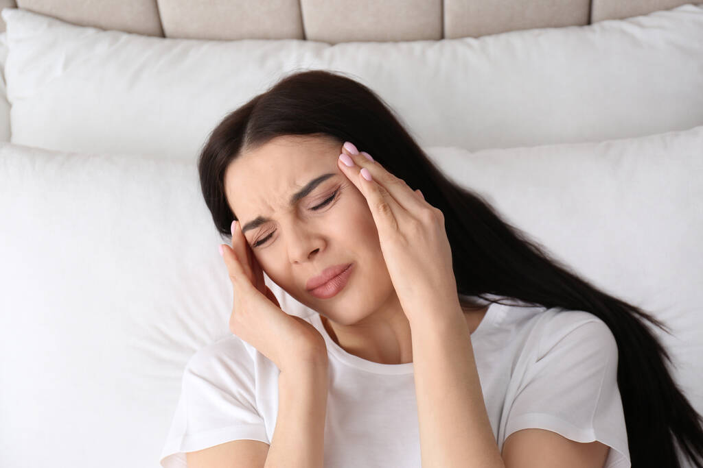 Młoda kobieta cierpiąca na migrenę w łóżku, widok powyżej - Zdjęcie, obraz