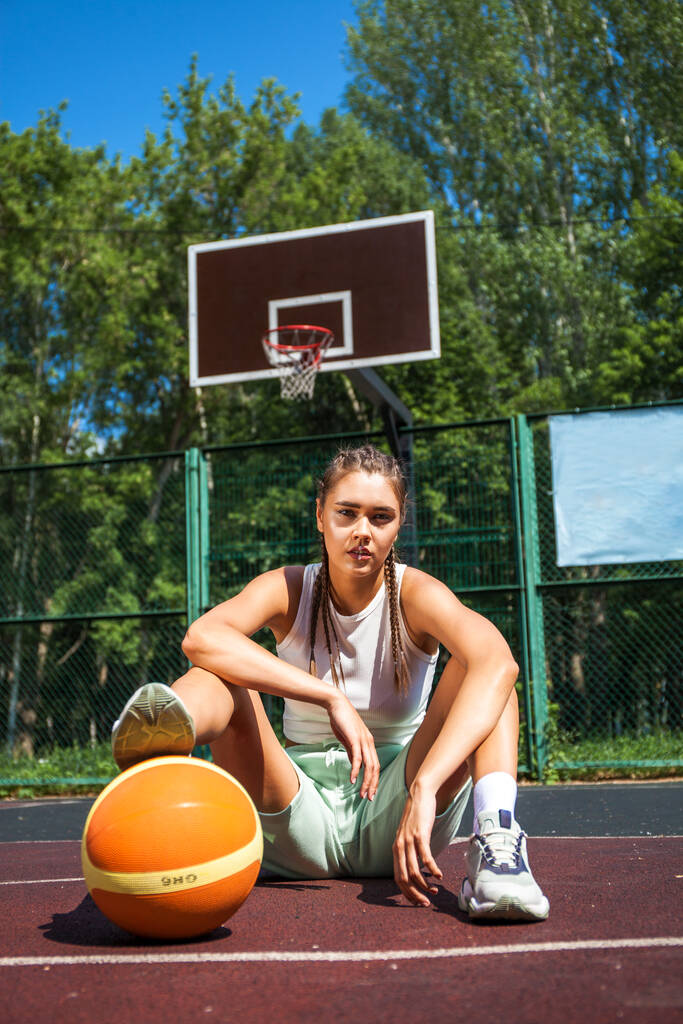 Молодая красивая брюнетка позирует на баскетбольной площадке - Фото, изображение