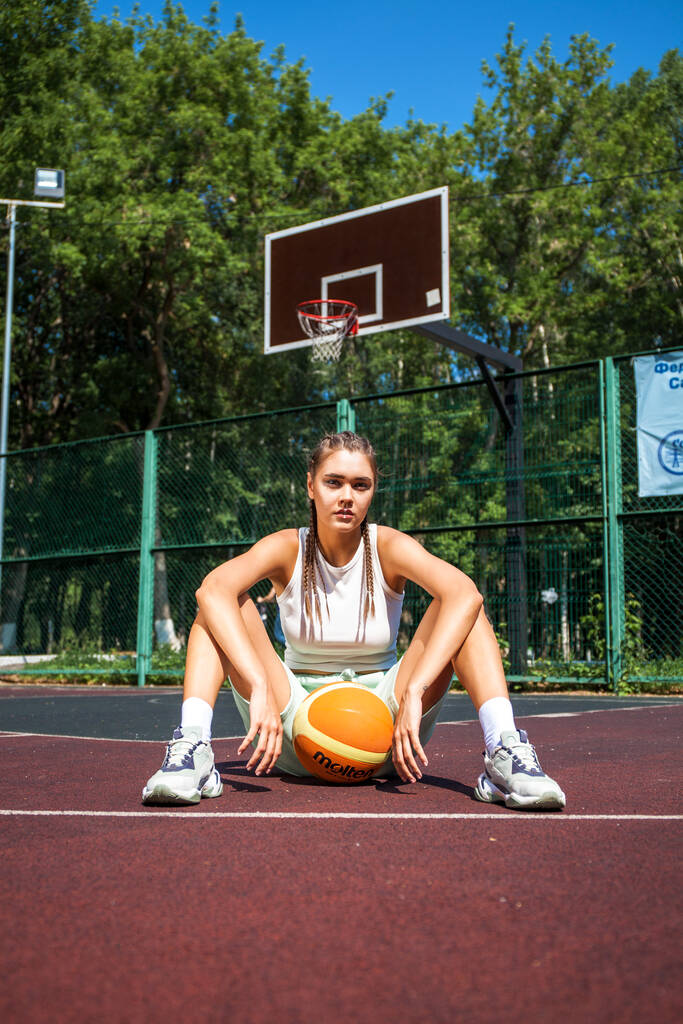 Молода красива брюнетка позує на баскетбольному майданчику
 - Фото, зображення