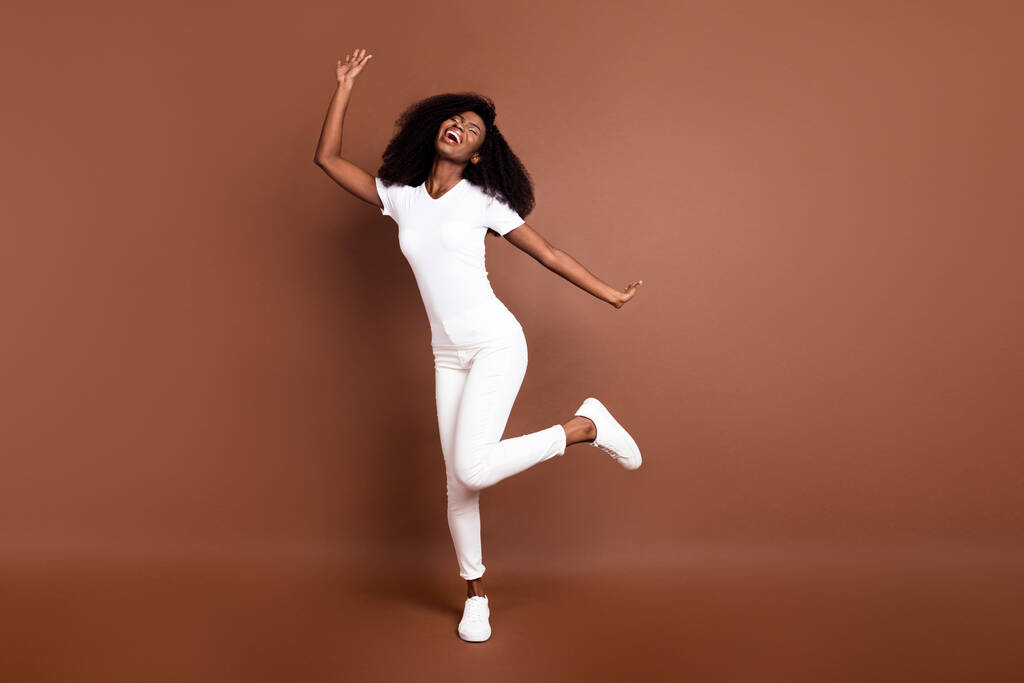 Full size foto di giovane eccitata ragazza nera felice sorriso positivo divertirsi ballare isolato su sfondo di colore marrone - Foto, immagini