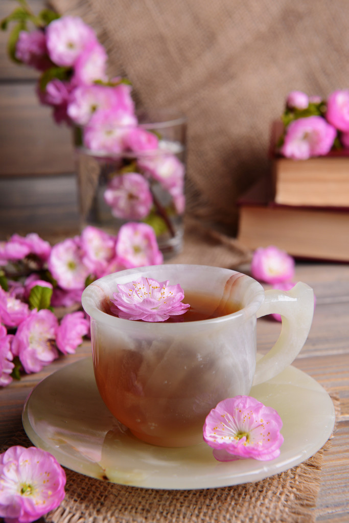 Mooie fruit blossom met kopje thee op tafel op grijze achtergrond - Foto, afbeelding
