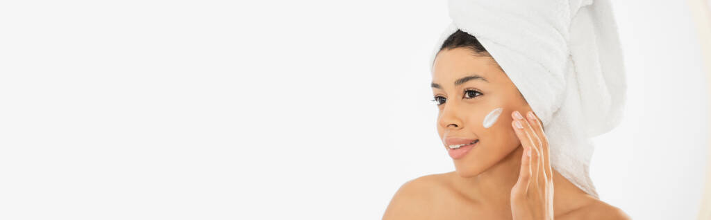 mosolygós fiatal afro-amerikai nő alkalmazó krém az arcon fehér háttér, banner - Fotó, kép