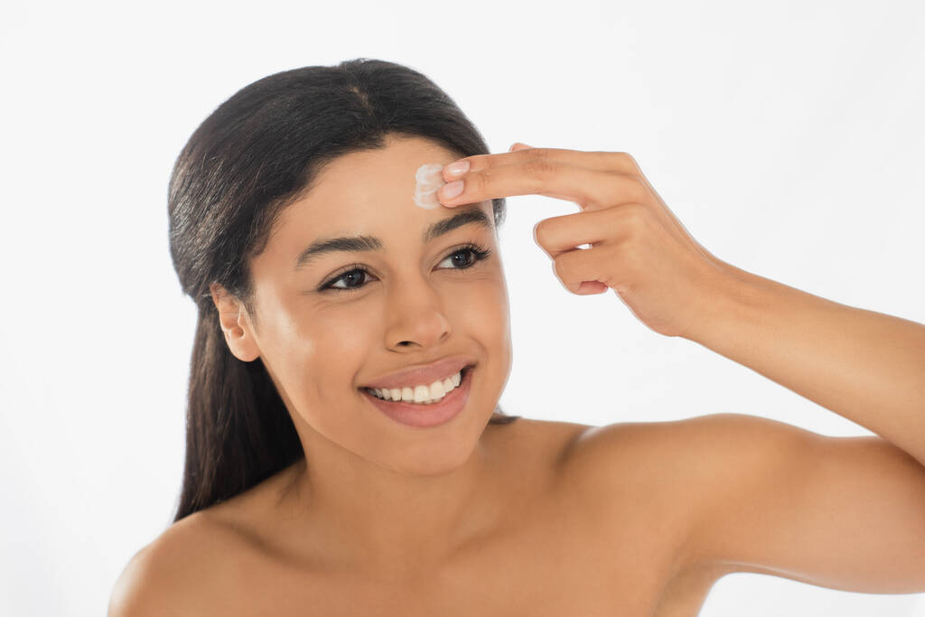 mosolygós fiatal afro-amerikai nő alkalmazó krém a homlokon fehér háttér - Fotó, kép