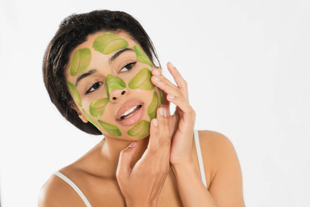 fókuszált fiatal nő alkalmazó zöld maszk az arcon kezek fehér háttér - Fotó, kép