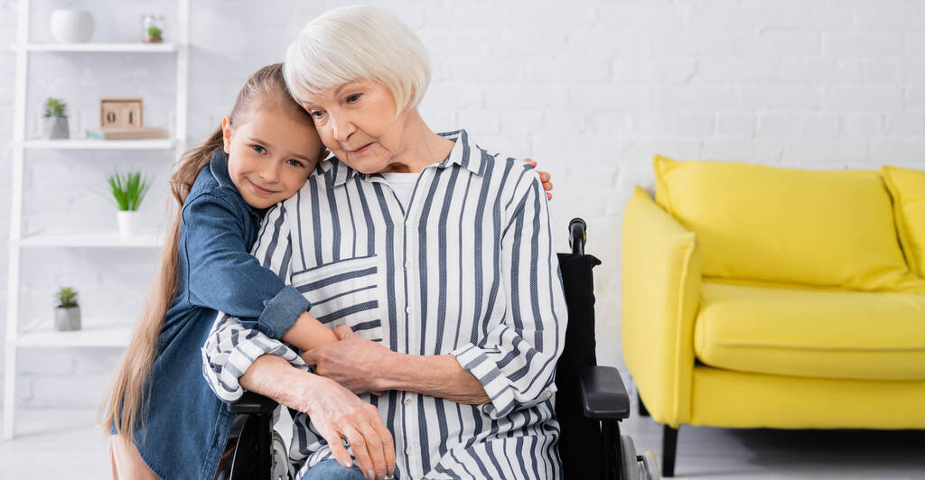 Hymyilevä lapsi halaa mummo pyörätuolissa, banneri  - Valokuva, kuva