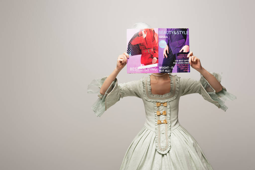 женщина в элегантном винтажном платье покрывая лицо с современной красотой и стиль журнала изолированы на сером - Фото, изображение