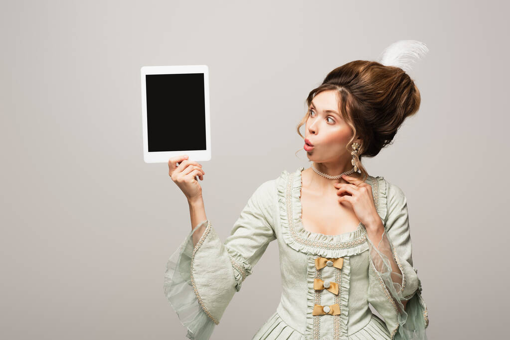 yllättynyt retro tyyli nainen etsii digitaalinen tabletti tyhjä näyttö eristetty harmaa - Valokuva, kuva