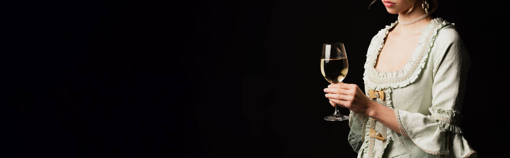 обрезанный вид в стиле ретро женщина с бокалом белого вина изолированы на черном, баннер - Фото, изображение