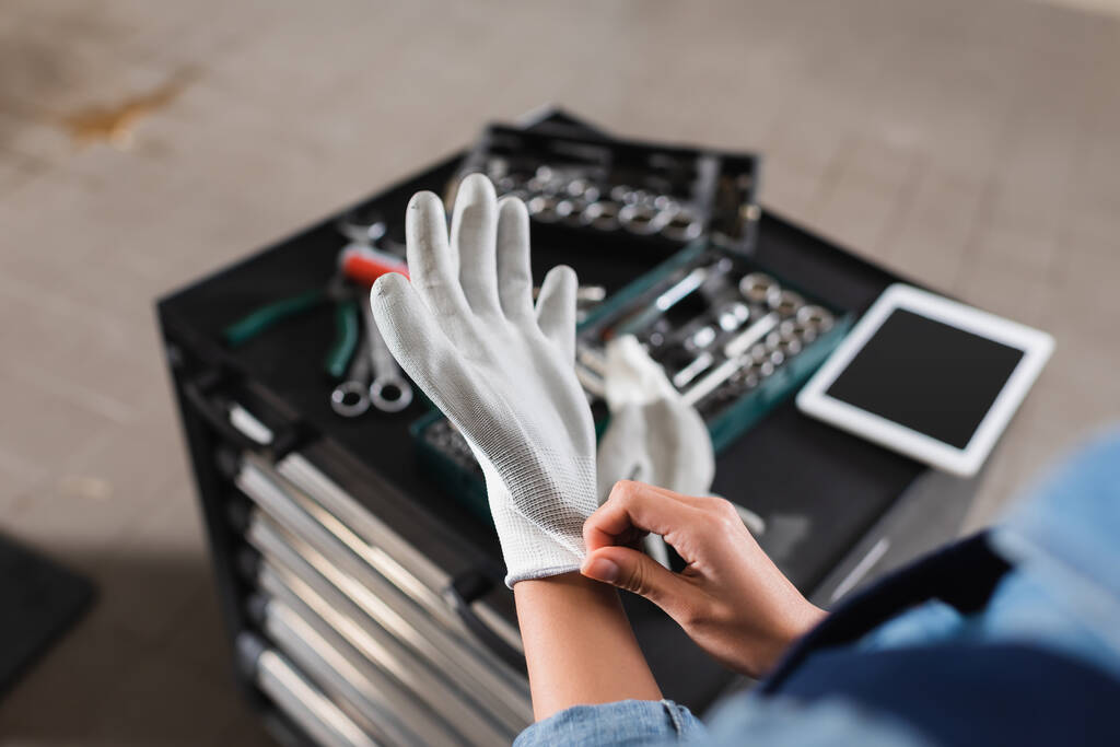 Alet çantasının yanında eldiven takan genç tamircinin kısmi görüntüsü ve garajda dijital tablet - Fotoğraf, Görsel