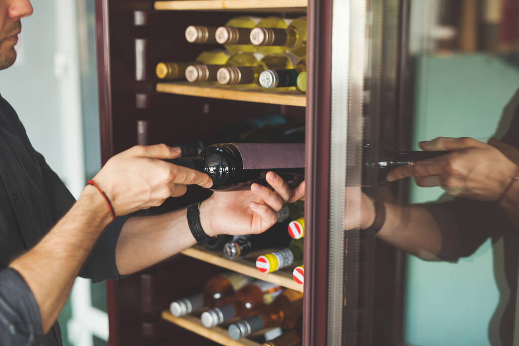 Mann wählt Flasche leckeren Wein in der Nähe Kühler im Geschäft - Foto, Bild