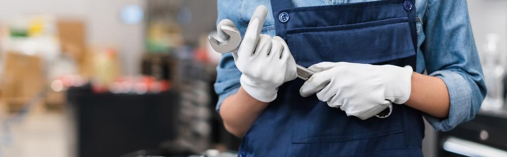 καλλιεργημένη άποψη του νεαρού μηχανικού με τα χέρια στα γάντια που κρατούν το κλειδί στην αυτόματη επισκευή υπηρεσία, λάβαρο - Φωτογραφία, εικόνα