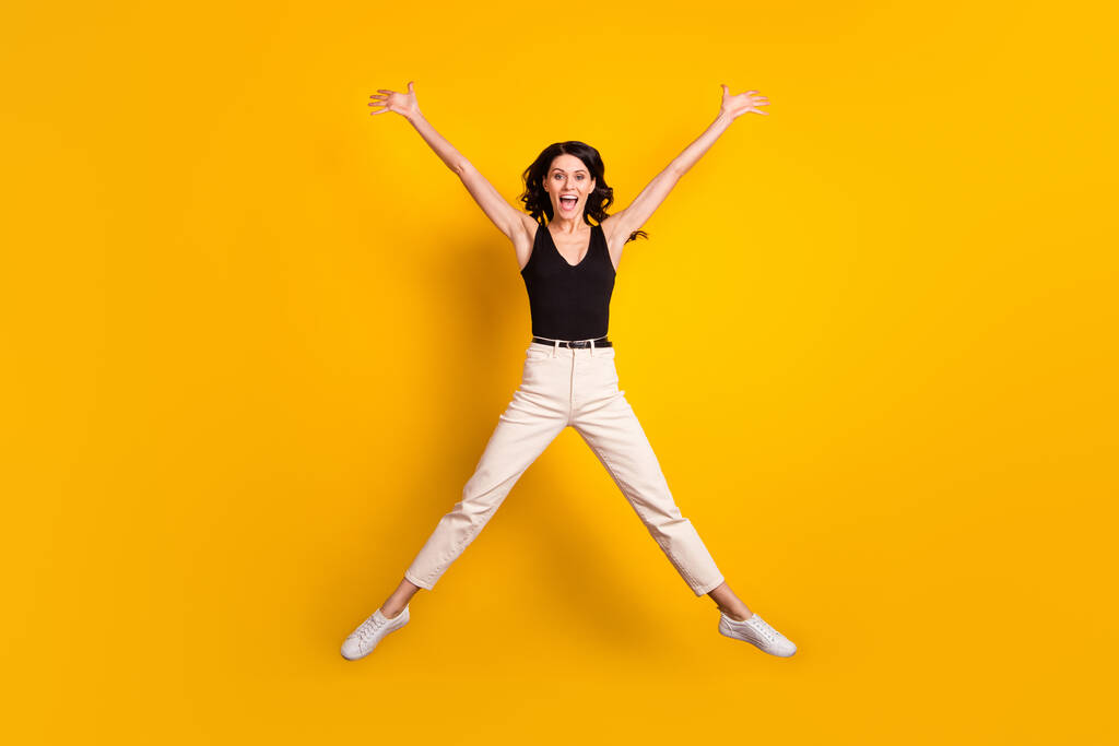 Plná velikost fotografie mladé vzrušené dívky šťastný pozitivní úsměv vyskočit izolované přes žluté barvy pozadí - Fotografie, Obrázek