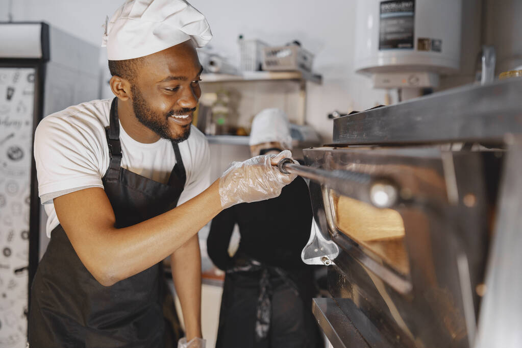 アフリカ系アメリカ人男性ベーキングピザに商業キッチン - 写真・画像