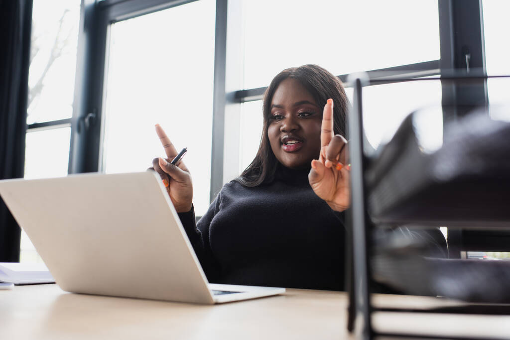 アフリカ系アメリカ人と大企業の女性がオフィスのノートパソコンでビデオ通話をしながら  - 写真・画像