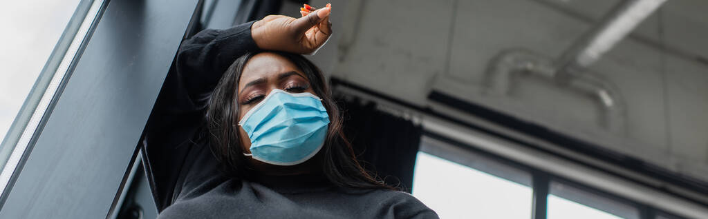 alacsony szög kilátás afro-amerikai plusz méret üzletasszony orvosi maszk érzés rossz az irodában, banner - Fotó, kép