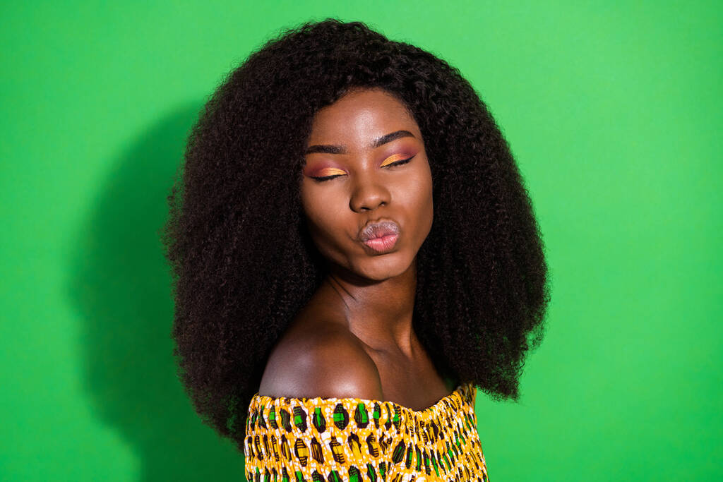 Genç, güzel, çarpıcı afro kadının fotoğrafı. Surat asan dudaklar. Yeşil arka planda izole edilmiş rüyalar. - Fotoğraf, Görsel