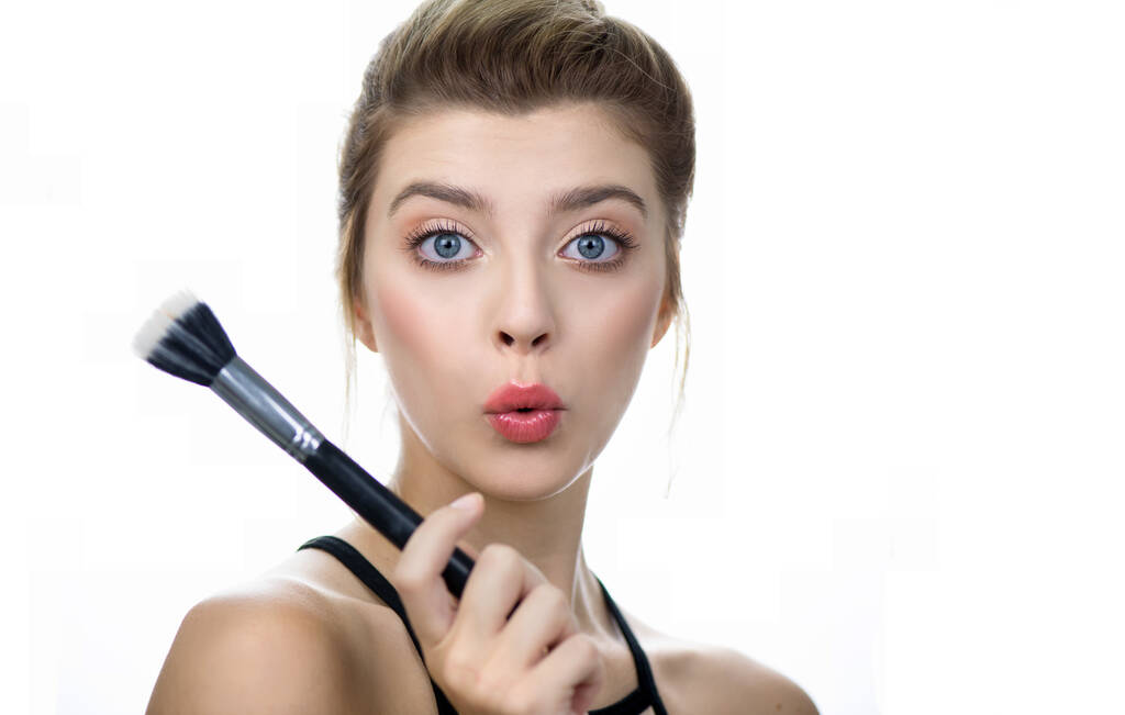 Porträt eines Schönheitsmodells mit Make-up und langen Wimpern mit Kosmetikpinsel in der Hand. Schöne junge Frau mit sauberer, perfekter Haut und Make-up. - Foto, Bild