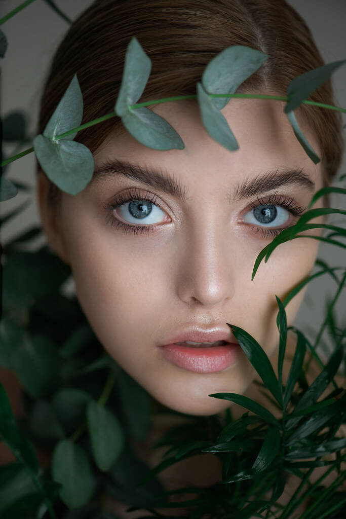 Muotokuva kauneus malli luonnon nude meikki eukalyptus lehtiä haara ja trooppisia kasveja. Kaunis nuori nainen puhdas täydellinen iho vihreät. Kylpylä, ihonhoito ja hyvinvointi. Sulje se.. - Valokuva, kuva