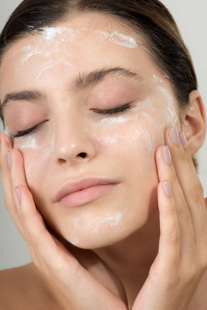 Jovem bonita cara de limpeza com espuma cosmética facial de cuidados com a pele, gel ou sabão. Mulher Hame SPA procedimentos. - Foto, Imagem