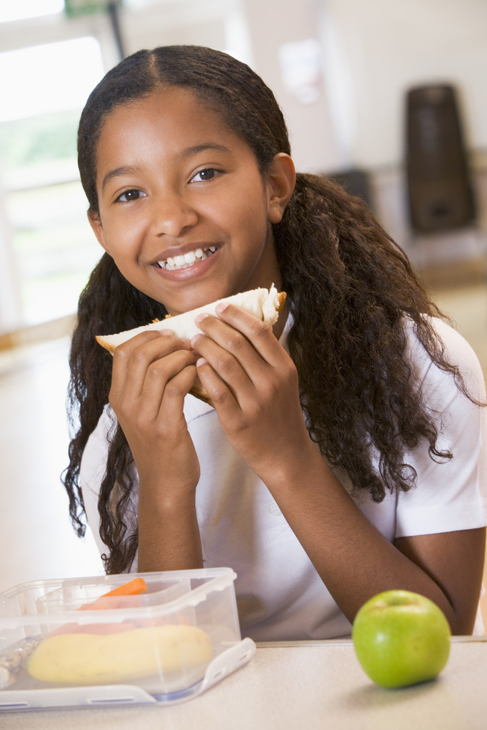 Schoolgirl enjoying her lunch in a school cafeteria - Photo, Image