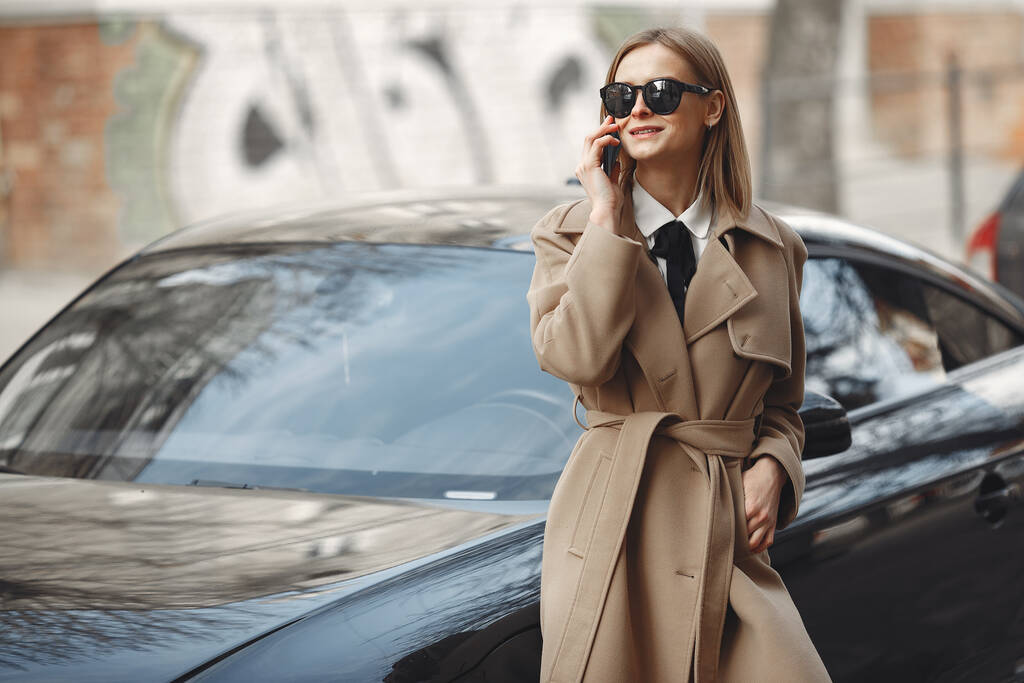 Elegáns nő barna kabátban egy tavaszi városban. - Fotó, kép