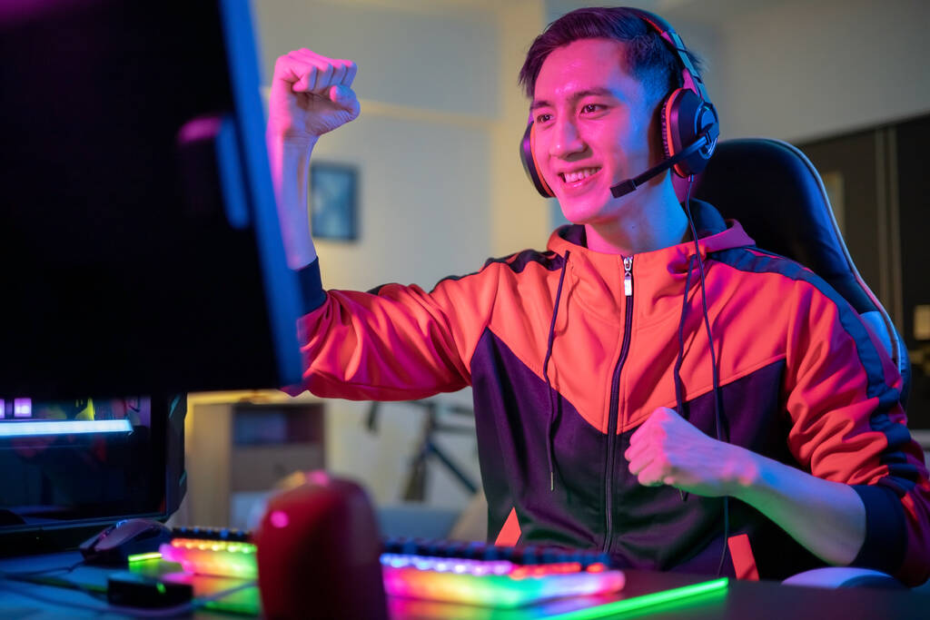 primer plano de Joven Asiático Guapo Pro Gamer se siente emocionado y levantando los brazos con el gesto de puño mientras juega en línea Cyber Sport Game en casa - Foto, imagen