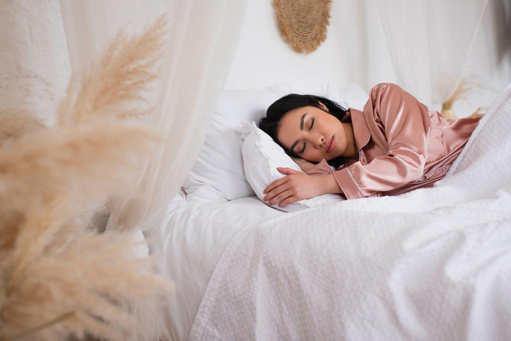 bonita joven asiática mujer en pijama de seda durmiendo en cama con ropa blanca en dormitorio - Foto, imagen