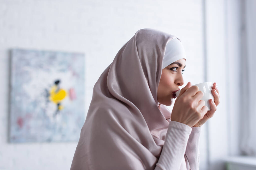 όμορφη μουσουλμάνα γυναίκα με χιτζάμπ πίνει τσάι στο σπίτι - Φωτογραφία, εικόνα