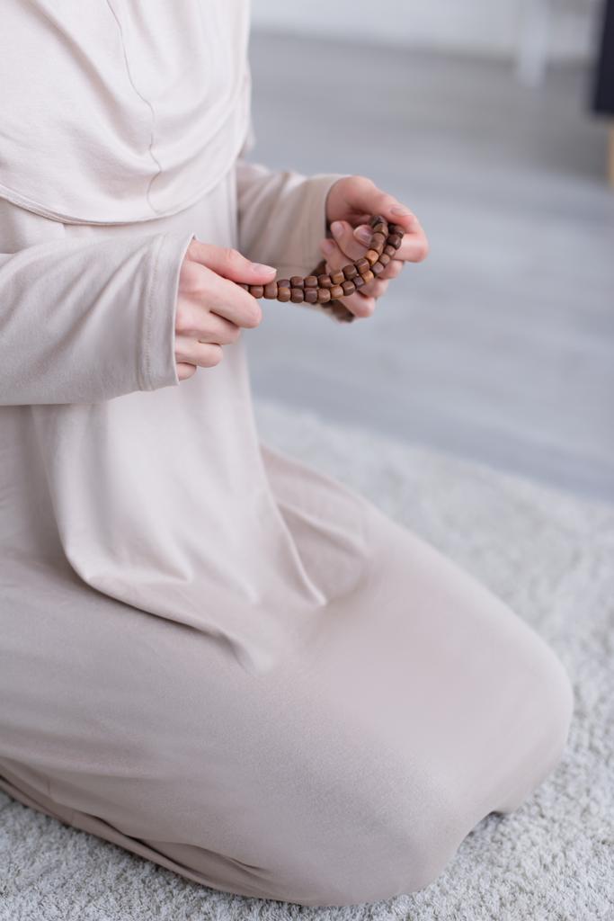 καλλιεργημένη άποψη των μουσουλμάνων γυναίκα προσεύχεται στα γόνατα στο σπίτι - Φωτογραφία, εικόνα