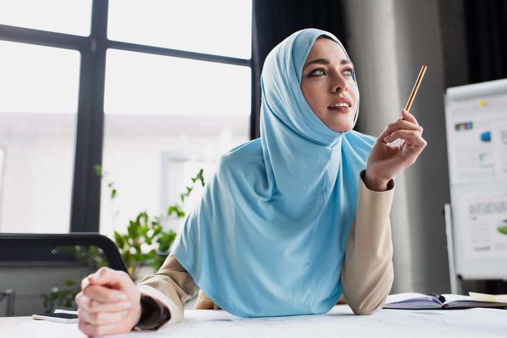 positieve moslim ingenieur houden pen tijdens het denken in het kantoor - Foto, afbeelding