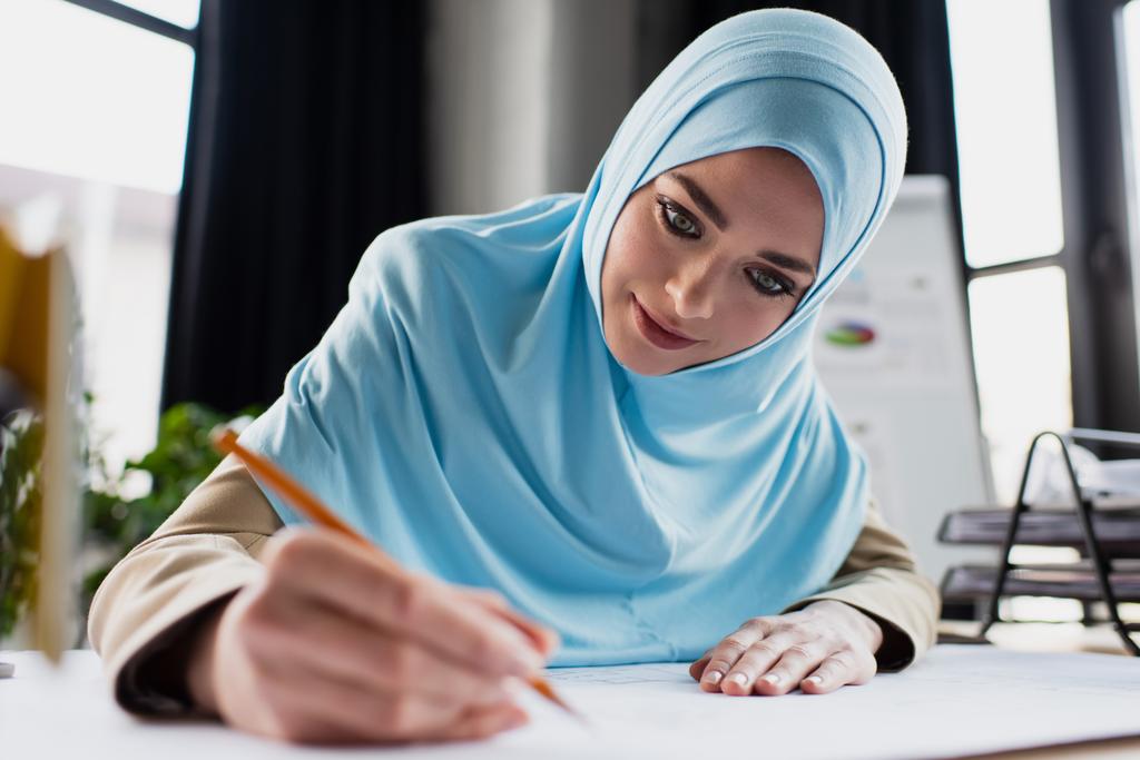 νεαρός μουσουλμάνος σχεδιαστής σχέδιο με μολύβι σε θολή πρώτο πλάνο - Φωτογραφία, εικόνα
