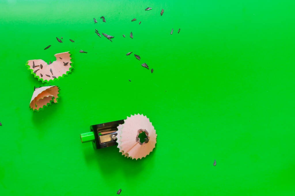 Een kort potlood in een slijper geplakt na verlangen, schoonmaken van een potlood op een groene achtergrond. - Foto, afbeelding