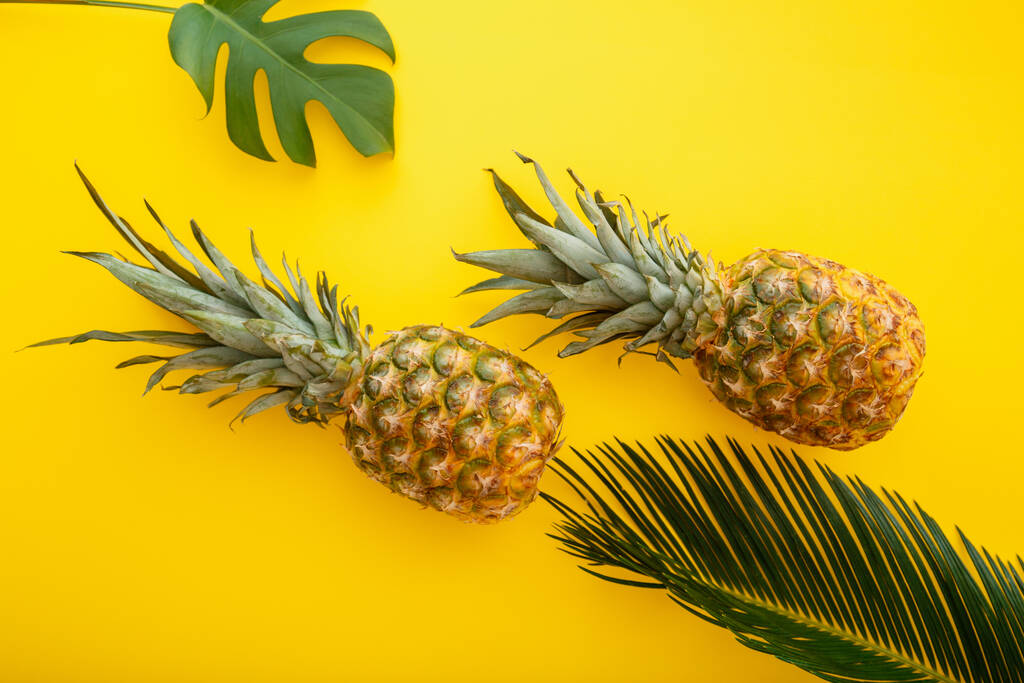 Ananas und Palmblätter auf gelbem Hintergrund. Tropische Sommer-Ananas Früchte flache Lagezusammensetzung. - Foto, Bild