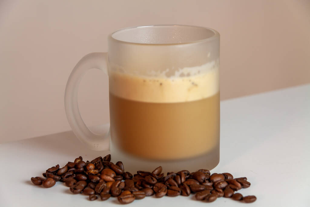 Крупный план чашки капучино и кофейных зерен - Фото, изображение