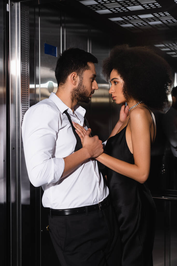 Бородатый мужчина трогает африканскую американскую подружку в лифте  - Фото, изображение