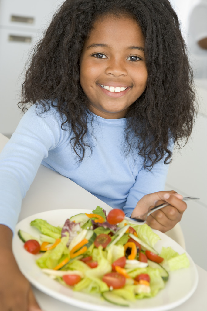 Giovane ragazza in cucina mangiare insalata sorridente
 - Foto, immagini