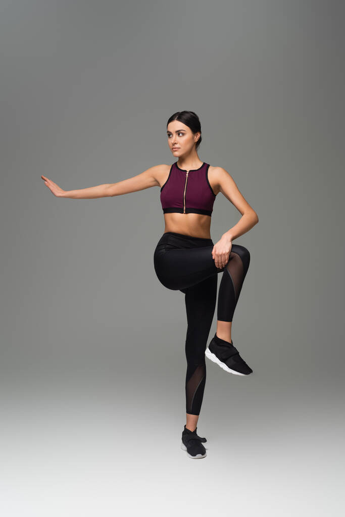 full length view of slim woman exercising on grey background - Photo, Image
