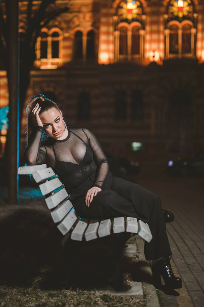 Вертикальный снимок сексуальной молодой женщины, позирующей на скамейке - Фото, изображение
