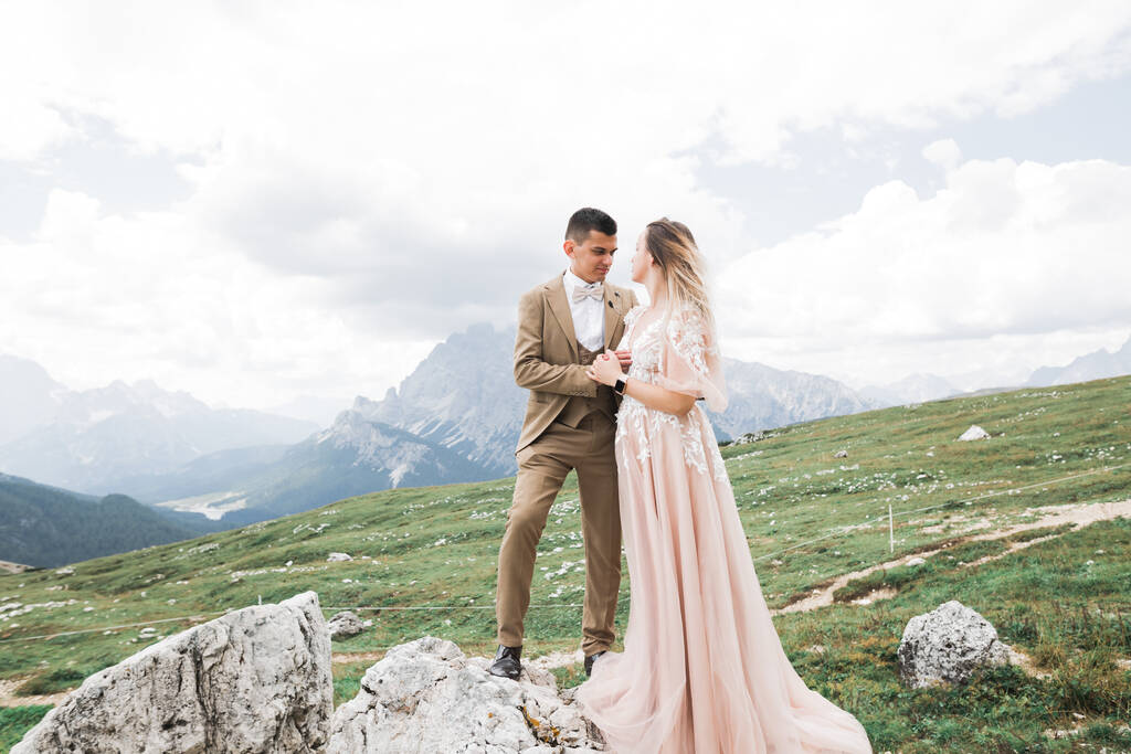 Όμορφη πανέμορφη νύφη που ποζάρει στον γαμπρό και διασκεδάζει κοντά στα βουνά με καταπληκτική θέα, χώρος για κείμενο, ζευγάρι γάμου - Φωτογραφία, εικόνα