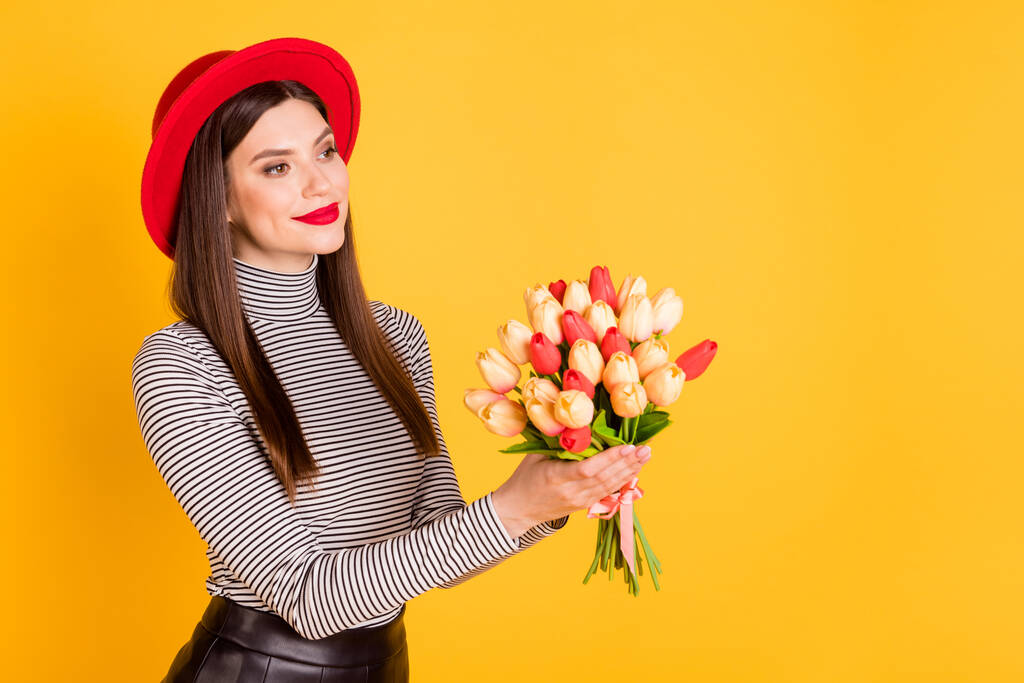 Profil boční fotografie mladé atraktivní dívka šťastný úsměv vypadají prázdné místo držet květiny kytice izolované přes žluté barvy pozadí - Fotografie, Obrázek